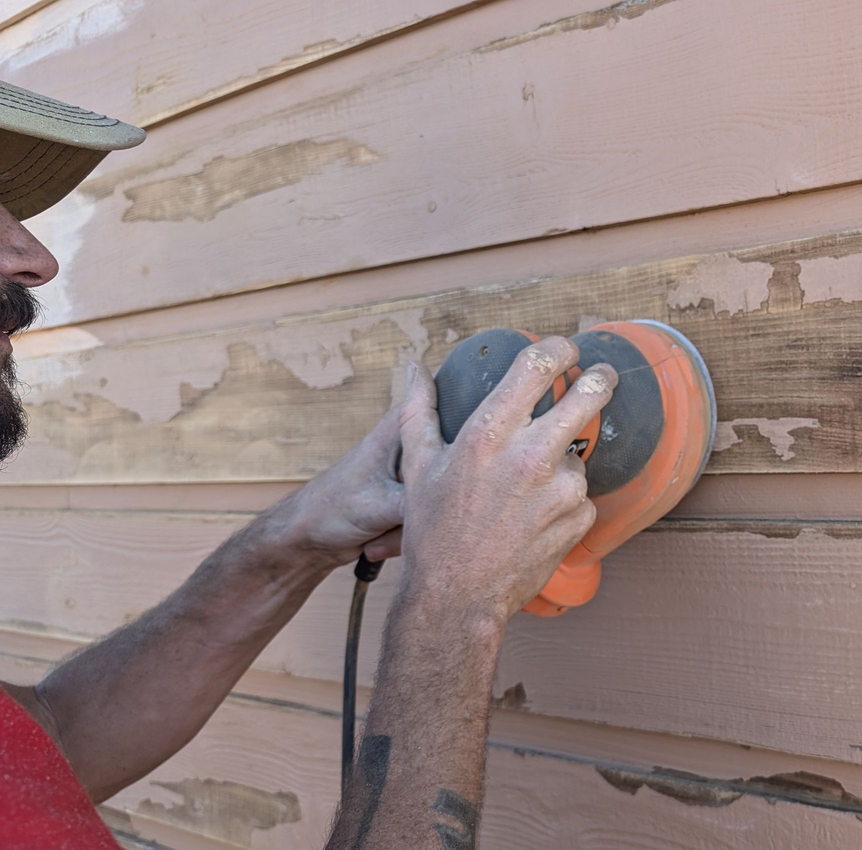 painter using a power sander on a wall to prep the surface